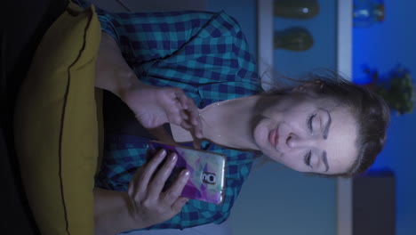 Vertical-video-of-Woman-using-social-media-on-phone-laughing-at-night-at-home.